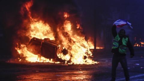 Overturned cars burn, as protesters wearing yellow vests (gilets jaunes) clash with riot police near the Arc de Triomphe as part of a demonstration over high fuel prices on the Champs Elysee in Paris, France, 01 December 2018