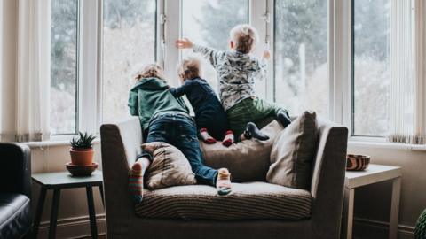 Three children looking out of a window.