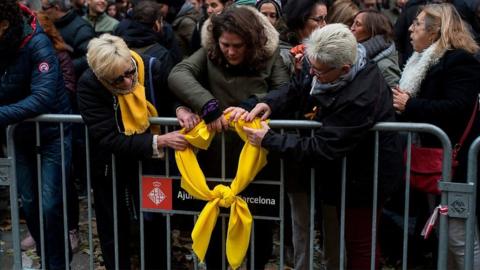 Women hang a yellow ribbon