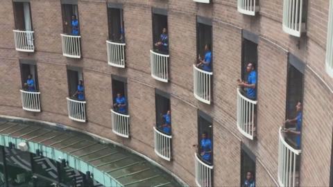 Rugby team singing from individual hotel balconies