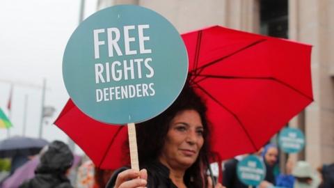 A woman holds a slogan that reads "Free rights defenders" outside Istanbul's court. Photo: 25 October 2017