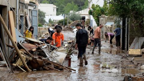 Locals remove debris on a street covered with muddy water in Sant Llorenc des Cardassar, on the Spanish Balearic island of Majorca