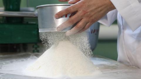 A man sifting flour onto a table