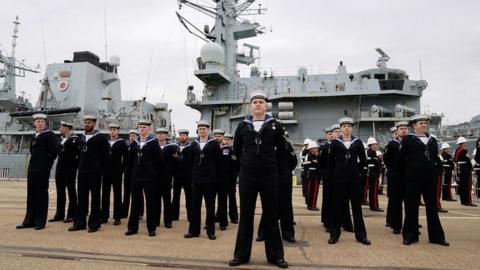 Members of the ship's company march past HMS Montrose