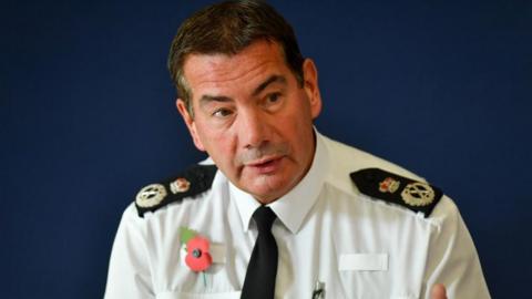 Nick Adderley with short dark hair wearing a police shirt, epaulettes and tie