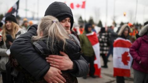 People hug as truckers and supporters continue blocking access to the Ambassador Bridge