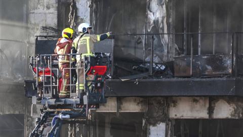 Firefighters check the facade of a building after the fire in Valencia