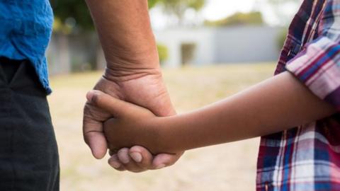 Close up child and adult hold hands