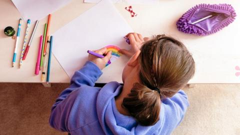 Girl drawing a rainbow with a felt-tip pen