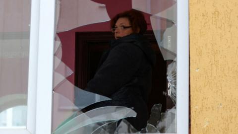 A woman looks out of a broken window in Belgorod
