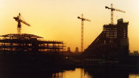 Three crane symmetry under construction at sunset