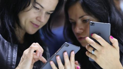 Visitors try out the Honor 7 smartphone at the Huawei stand at the 2015 IFA consumer electronics and appliances trade fair on September 4, 2015 in Berlin, Germany.