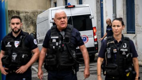 Police officers establish a security perimeter in front of the courthouse in Valence as the convoy carrying Gabriel Fortin arrives