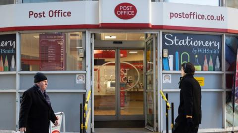 People walking past a Post Office branch