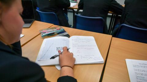 Girl writes in her school book during a class