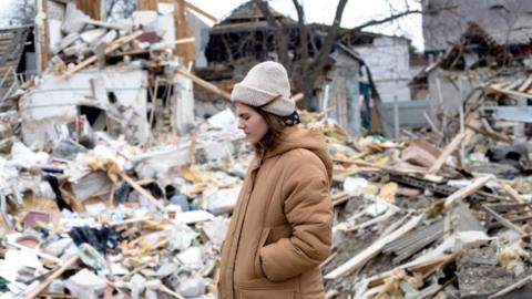 A resident stands in front of rubble following the shelling of buildings by Russian forces in Markhalivka, Ukraine, 5 March 2022