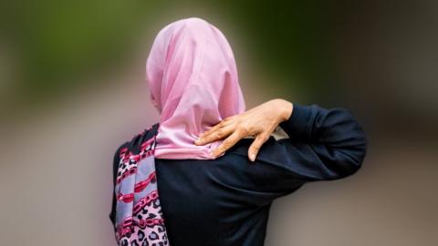 Paranda walks down the street wearing her pink scarf