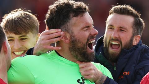 Ben Foster of Wrexham celebrates saving a penalty for Wrexham against Notts County