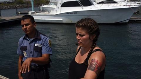 Alice Ottz, a member of the organization Women on Waves, speaks with a private guard at the Pez Vela Marina in the port of San Jose,