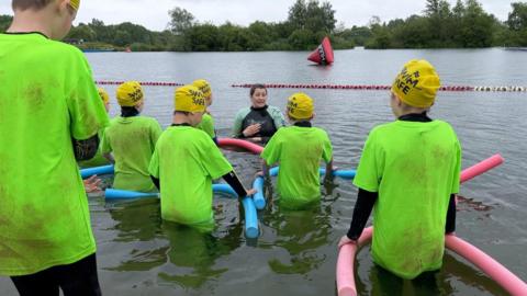 Children and Instructor in the lake with noodle floats 