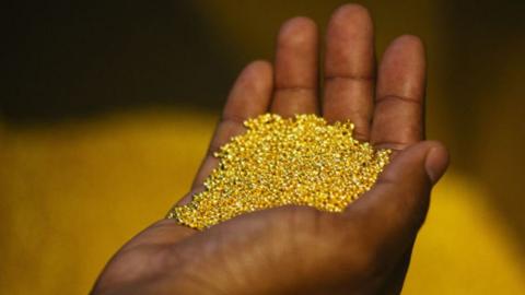 A man cradles gold bead in his hands.