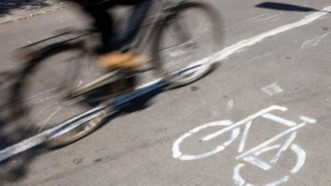 An image of a moving bicycle passing a bicycle sign, which is painted in white on the ground.