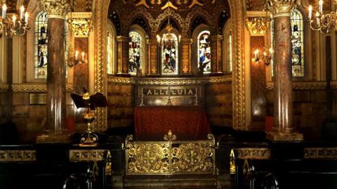 A richly furnished interior of a chapel, with marble pillars and stained glass windows. 