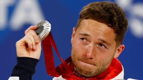 Alfie Hewett holds up his Paralympic silver medal in the medal ceremony after his singles final defeat