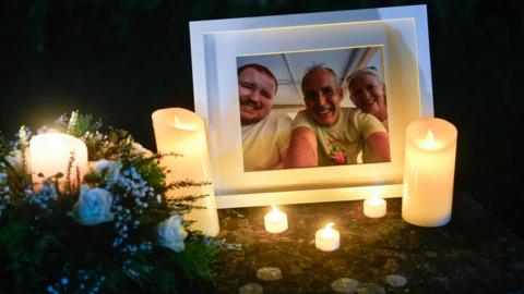 Candles burn next to a photo during a vigil in Louth for Mark and Louise O'Connor and their son Evan