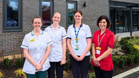 Four health professionals standing outside a clinic.
