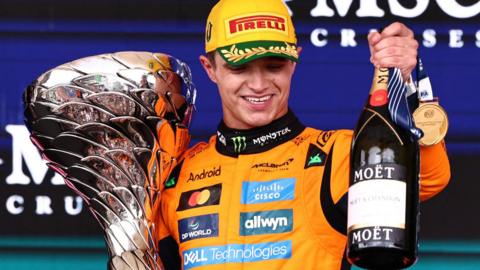 Lando Norris holds the winner's trophy and a bottle of champagne after winning the Sao Paulo Grand Prix