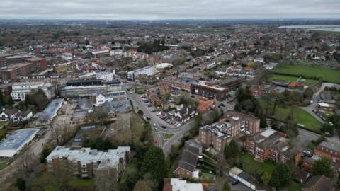 Walton is seen in an aerial shot with low rise buildings, some houses and playfields with a road going through the middle of it.