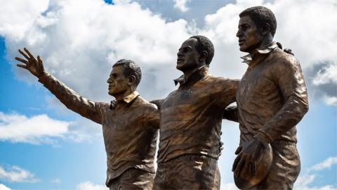 The statue in Cardiff Bay of Gus Risman, Billy Boston and Clive Sullivan former rugby league players from south Cardiff
