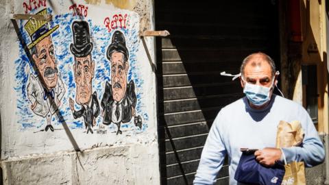 A person wearing a protective face mask walks at Quartieri Spagnoli, Naples, Italy, 18 March 2020