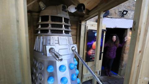 Museum co-owner Lisa Cole stands next to the Dalek and shed