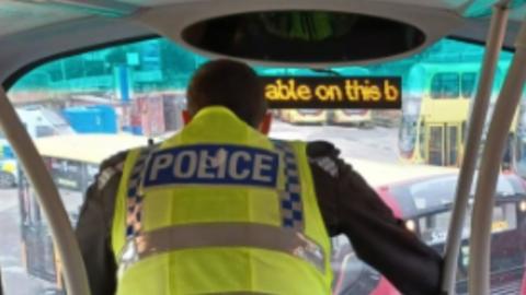 Police officer on the top floor of a double-decker bus