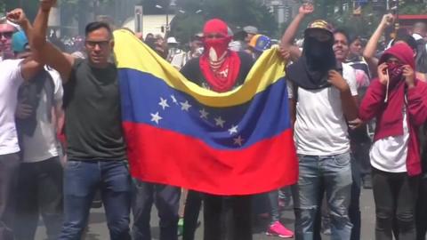 Anti-government protesters in Caracas wave a Venezuelan flag