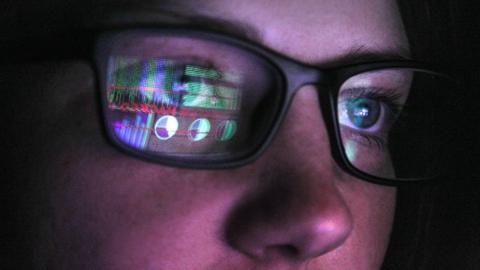 Computer screen reflected in a woman's glasses