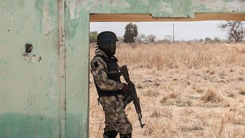 A soldier stands next to the ruins of Government Girls Secondary School Chibok in 2016.