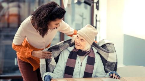 Woman covering an elderly woman with a blanket