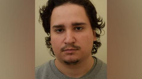 Gabriel Budasz' mug shot. He is wearing a grey shirt and has dark hair.