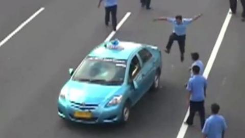A striking Indonesian taxi driver kicking a taxi