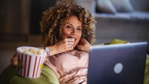 A stock image of someone watching a flim on a laptop computer