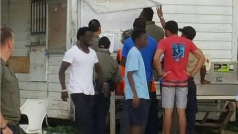 A supplied photo of refugees at Manus detention centre checking a notice board