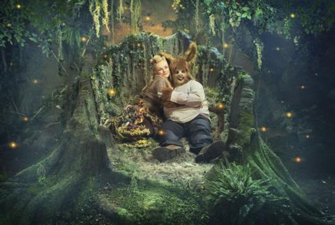 Maxine Peake as Titania and Matt Lucas as Bottom hugging in a tree stump, surrounded by fireflies  