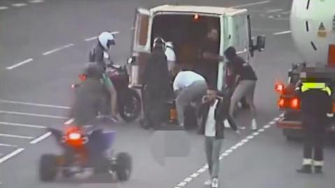 People loading a motorbike into the back of a van