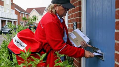 A Royal Mail post woman delivering post