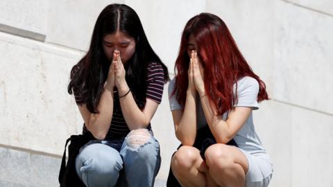 South Korean women praying on the banks of the Danube after a tour boat sank in Budapest