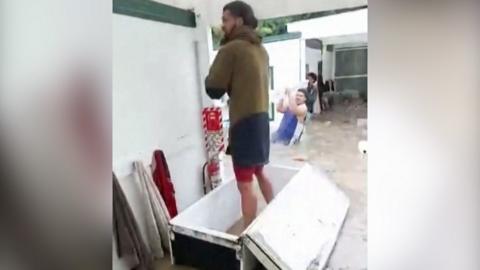 A trapped man floats on a fridge through flood waters in New Zealand during Cyclone Gabrielle