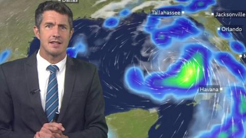 Chris Fawkes in front of a ˿ Weather map showing Hurricane Idalia north-west of Cuba